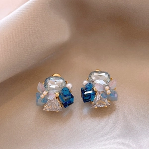 Close-up of 18k gold plated earrings featuring blue crystals, pearls and tulle butterflies