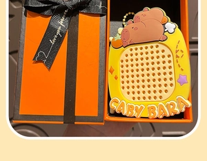 Close-up of a yellow cartoon Capybara portable device inside an orange gift box