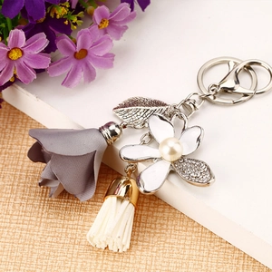 Detail of floral keychain with fabric rose, enamel flower, pearl and white tassel
