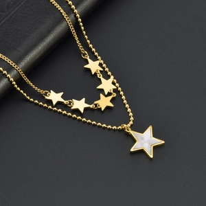 Detail of double-layer gold necklace with white shell star pendant on leather background