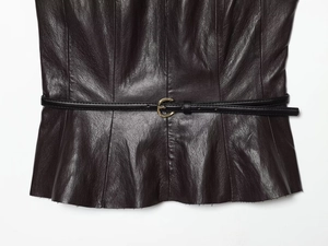 Détail d'un haut en cuir marron foncé avec ceinture noire fine et boucle dorée ronde