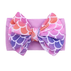 Detailed view of baby headband featuring purple waffle texture and fish scale bow print
