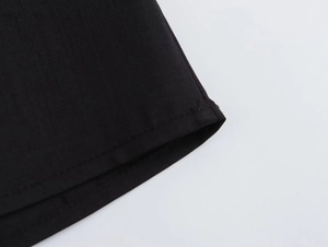 Vue détaillée de la texture du tissu sergé noir et des coutures de l'ourlet de robe