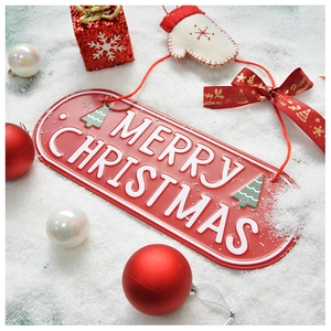 Macro shot of a red Merry Christmas sign on snow with festive ornaments and ribbons