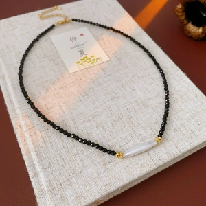 Close-up of black faceted crystal necklace with white baroque pearl and gold hardware