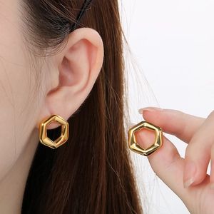 Close-up of minimalist 18K gold plated hexagonal stud earrings worn by a model