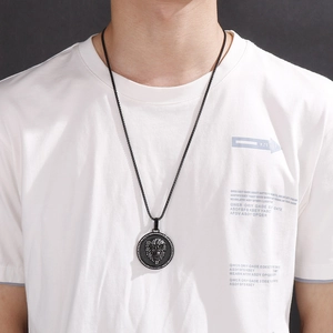 Macro view of a matte black lion head shield pendant necklace on a male model