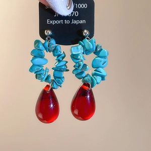 Detail of silver drop earrings with blue turquoise stones and red resin teardrop pendant