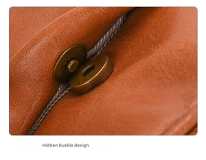 Detailed macro view of the hidden magnetic buckle on a brown leather business backpack