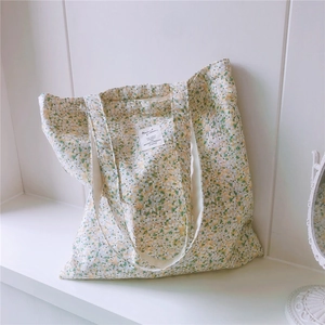 Detail showing floral cotton canvas tote bag with decorative woven label and dual straps