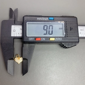 Macro view of crystal zircon heart pendant being measured with a digital caliper for size