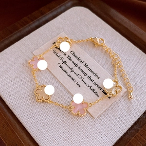 Detail of gold flower bracelet featuring pink clover charms and adjustable lobster clasp closure
