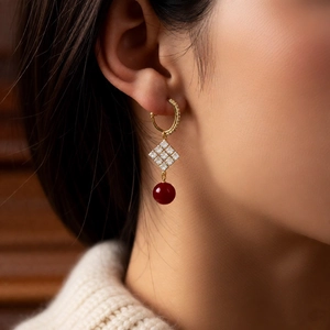 Détail de la boucle d'oreille plaquée or 18 carats avec motif losange et perle rouge