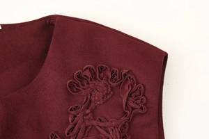 Detailed close-up of wine red vest featuring textured fabric and ruffled trim details