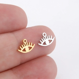 Miniature gold and silver evil eye charms for DIY jewelry making on fingertip