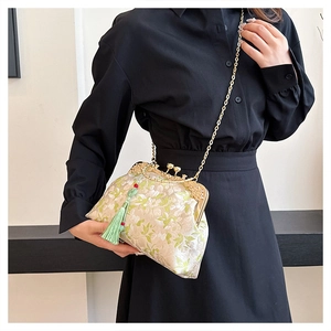 Detail of floral embroidery on beige brocade bag with gold frame and green tassel