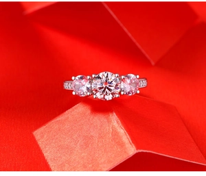 Close-up of a 925 silver three-stone moissanite ring with side accent stones on red background