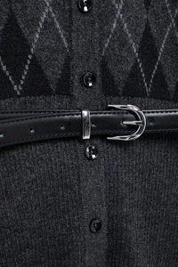 Detail of dark grey diamond-knit cardigan with black leather belt and metallic buckle