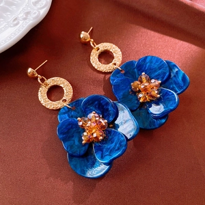 Detail of blue resin flower earrings with marble texture and golden hammered metal loops