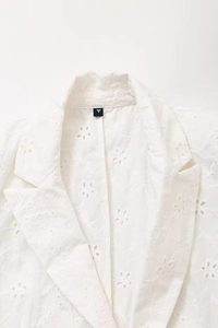 Close-up of white blazer collar featuring intricate floral hollow embroidery detail