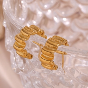 Gros plan de boucles d'oreilles créoles en acier plaqué or 18K avec texture ondulée