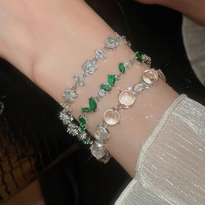 Gros plan de trois bracelets avec zircons, émeraudes et opales portés au poignet
