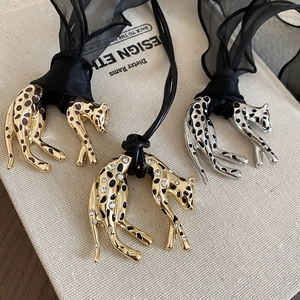 Detailed view of leopard pendants with enamel and rhinestones on silk ribbon necklace