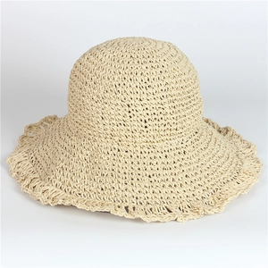 Detailed close-up of woven paper straw texture on a wide-brimmed beach hat in beige