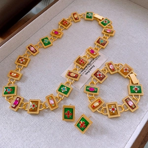Detail of vintage gold jewelry set with enamel squares and rhinestones on display tray