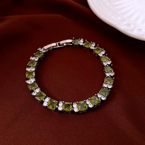 Detail of silver tennis bracelet with oval olive green stones on red silk fabric