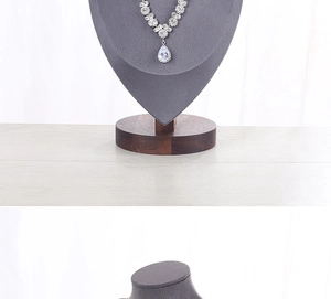Macro view of gold and silver pendant necklaces on grey bust stands with wood bases