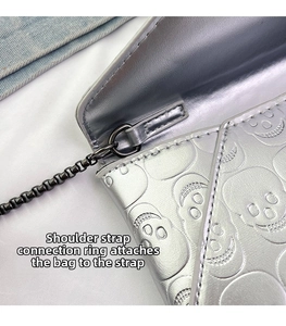 Detail of metal link and gun-black chain connector on silver skull embossed handbag