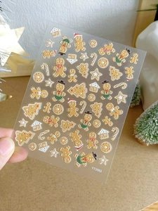 Detail view of 3D Christmas gingerbread man and star nail art stickers held over wood background