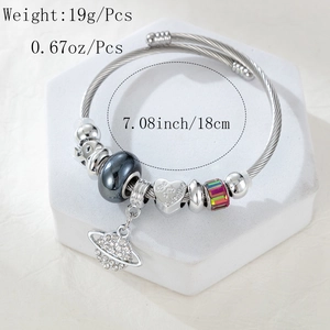 Detail of beaded steel bracelet with Be My Valentine heart and Saturn charm on a white stand
