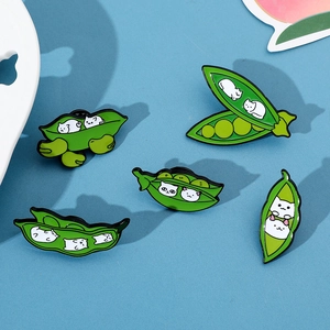 Detailed view of five creative green pea pod enamel brooches featuring white cartoon cats