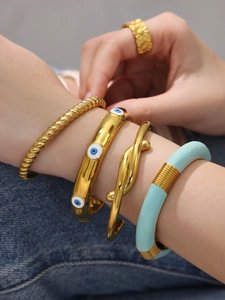 Dettaglio di bracciali rigidi smaltati con occhio del male e anello dorato vintage