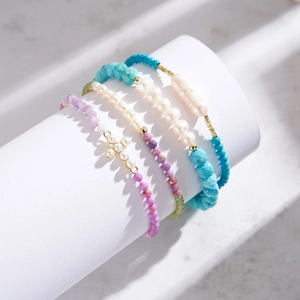Detail of baroque pearl bracelets with turquoise and cross-shaped pearl accents