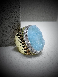 Macro view of blue druzy crystal ring with hammered gold band and pavé detailing