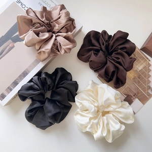 Close-up of four oversized satin scrunchies in champagne, coffee, black, and beige colors
