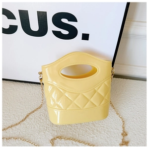 Dettaglio mini borsa a secchiello gialla in PVC con motivo trapuntato e catena d'oro