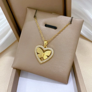Close-up of golden heart pendant with hollow butterfly and crystals in gift box