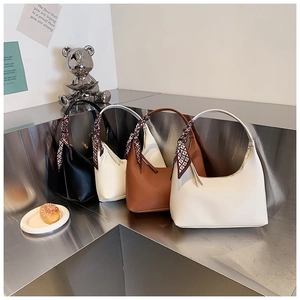 Detailed view of four minimalist shoulder bags with silk scarves on silver steps