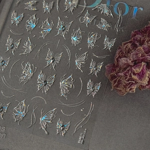 Macro shot of laser silver butterfly nail stickers with 3D embossed metallic texture