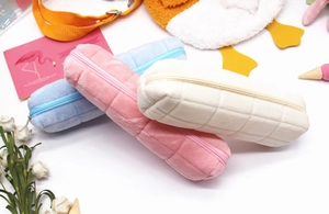 Macro detail of plush checkered pencil cases in pink, blue and beige soft fabric