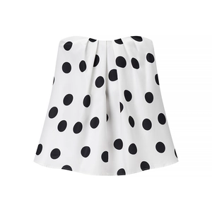 Détail d'une jupe en satin blanc à pois noirs avec de larges plis à la taille ajustée