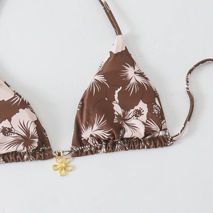 Detail of tropical hibiscus print bikini top with a gold flower pendant and tie straps