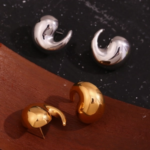Close-up of gold and silver irregular swirl earrings with a polished metallic finish