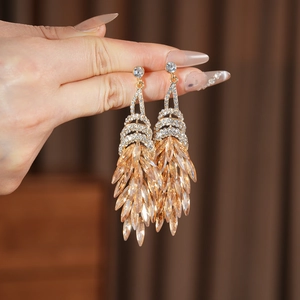 Détail de boucles d'oreilles longues de luxe avec cristaux de couleur champagne