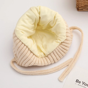 Beige gestrickte Baby-Mütze mit gelbem Warmfutter und praktischen Bindebändern