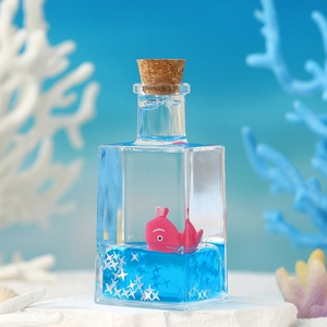 Ocean-themed square liquid bottle with pink whale and silver stars on white surface